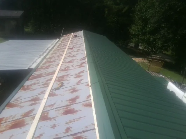 Old rusted panels beside newly installed green metal roofing — Wind Damage Roof Repair by Roofing Brothers in Chatfield