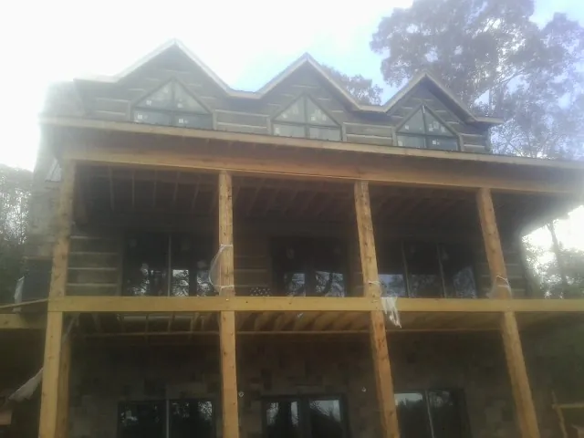 Dormers and porch framing on a large log home under construction — Roof Coating work by our crew in Chatfield